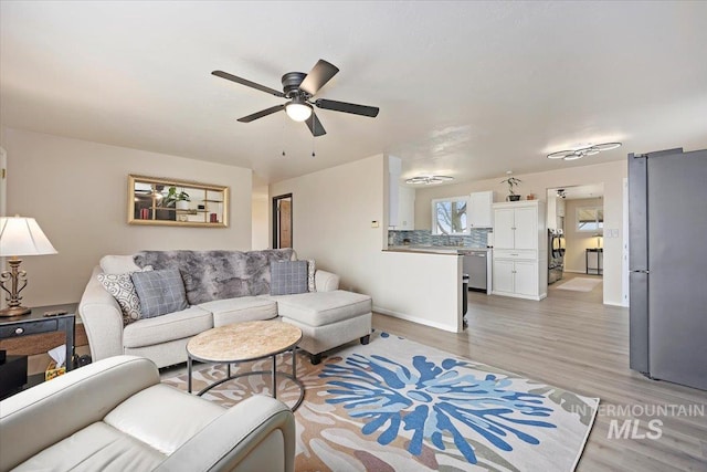 living area with light wood-style flooring, baseboards, and a ceiling fan