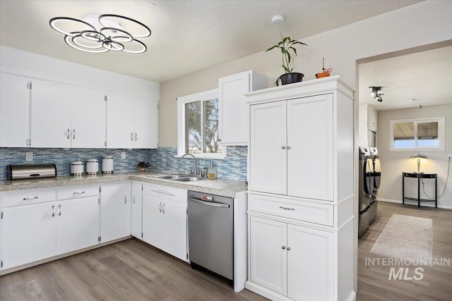 kitchen with a sink, white cabinets, light countertops, decorative backsplash, and dishwasher
