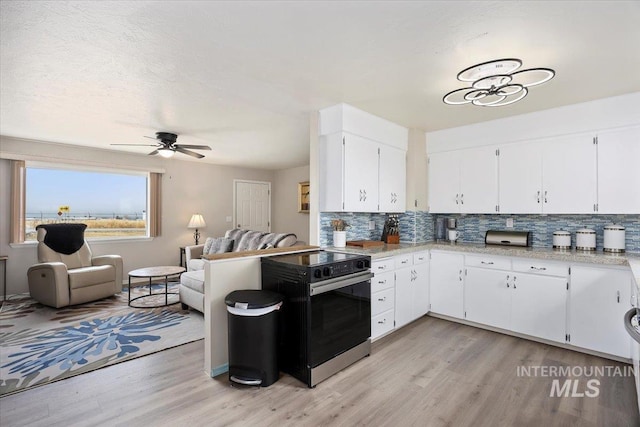 kitchen featuring black / electric stove, tasteful backsplash, open floor plan, and light countertops