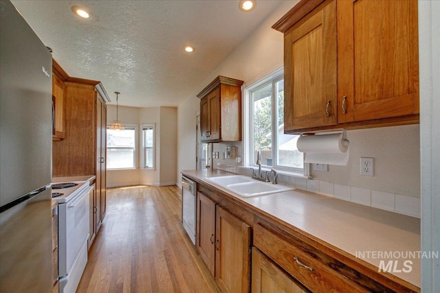 1239 Willow Creek Dr, Nampa, ID 83686 - kitchen with appliances with stainless steel finishes, a sink, brown cabinets, light wood-style floors, and pendant lighting