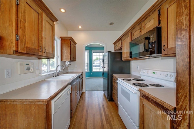 1239 Willow Creek Dr, Nampa, ID 83686 - kitchen featuring white appliances, a sink, brown cabinetry, light wood-style floors, and light countertops