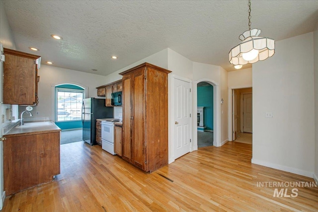 1239 Willow Creek Dr, Nampa, ID 83686 - kitchen with black appliances, arched walkways, a sink, light wood-style floors, and brown cabinetry