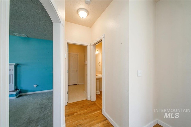 1239 Willow Creek Dr, Nampa, ID 83686 - corridor with baseboards, arched walkways, light wood finished floors, and a textured ceiling