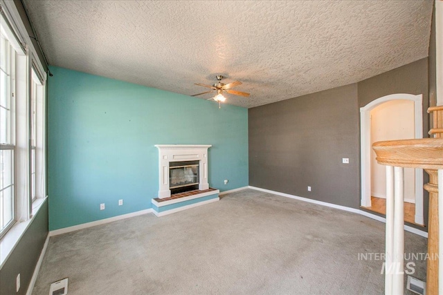 1239 Willow Creek Dr, Nampa, ID 83686 - unfurnished living room with a ceiling fan, carpet flooring, healthy amount of natural light, a glass covered fireplace, and a textured ceiling