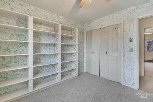 unfurnished bedroom with ceiling fan, carpet, a textured ceiling, and a closet