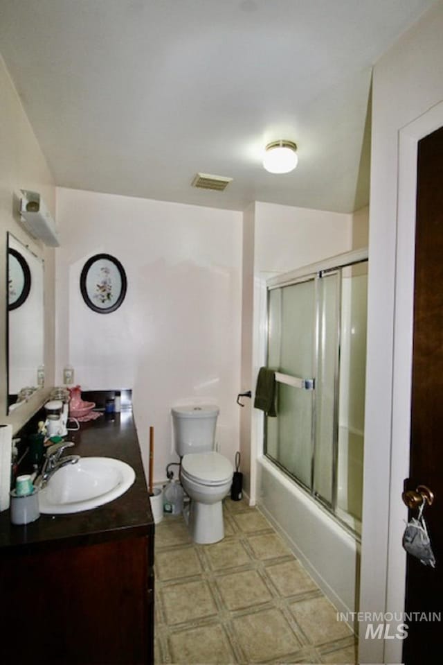 full bathroom featuring toilet, vanity, and shower / bath combination with glass door