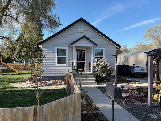 bungalow-style home with a playground, fence, and a front yard