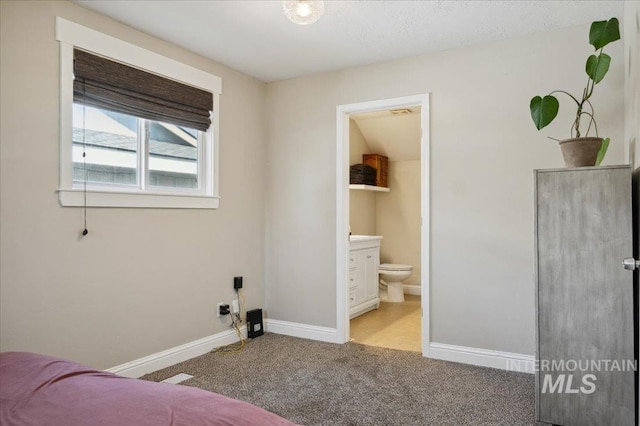 carpeted bedroom with baseboards and ensuite bath