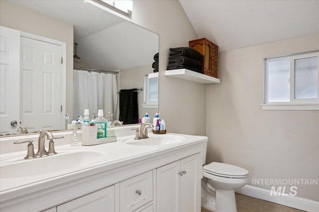 bathroom featuring a sink, vaulted ceiling, toilet, and double vanity