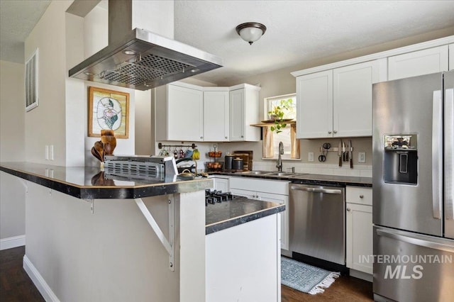 kitchen featuring dark countertops, appliances with stainless steel finishes, range hood, a sink, and white cabinets