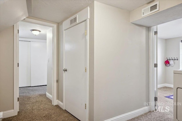 corridor featuring carpet floors, baseboards, washer and clothes dryer, and visible vents