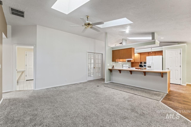 1548 N Vineyards Ave, Meridian, ID 83642 - unfurnished living room featuring a skylight, vaulted ceiling, a textured ceiling, ceiling fan, and baseboards