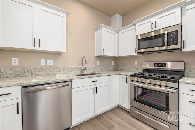 1438 N Cole Cottage Ln, Boise, ID 83704 - kitchen featuring appliances with stainless steel finishes, a sink, light wood finished floors, white cabinetry, and light stone counters
