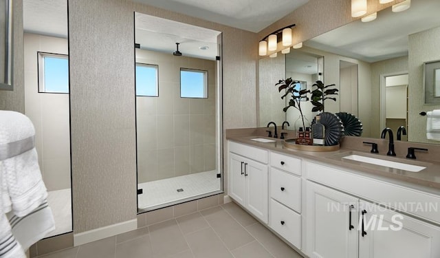 full bathroom with double vanity, tile patterned flooring, a walk in shower, and a sink