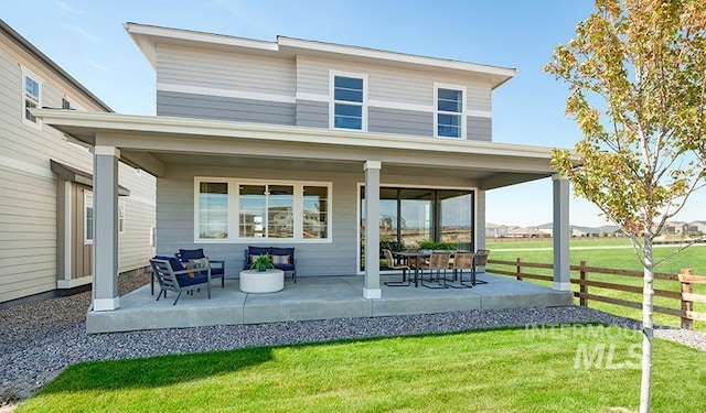 rear view of house featuring a patio area, fence, and a lawn