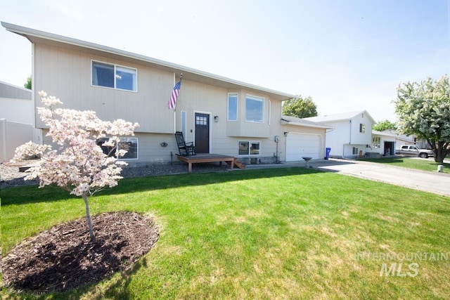 raised ranch with a garage, a front lawn, and concrete driveway