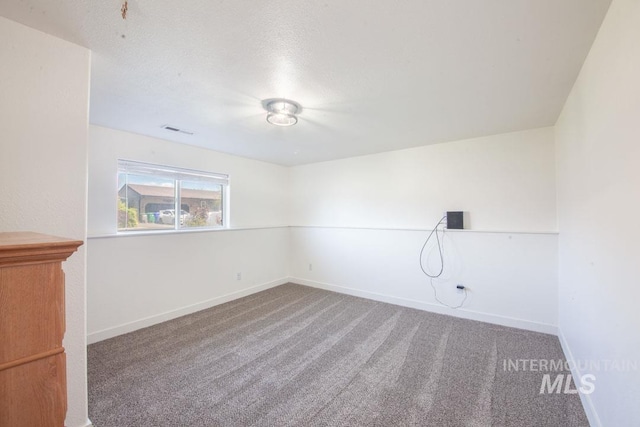 unfurnished room with carpet flooring, a textured ceiling, baseboards, and visible vents