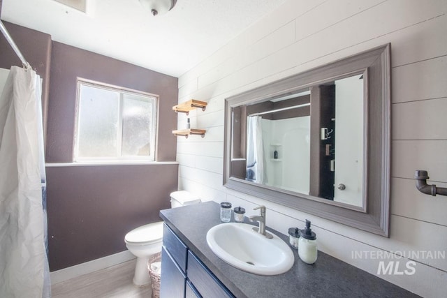 bathroom with vanity, toilet, wood walls, and curtained shower