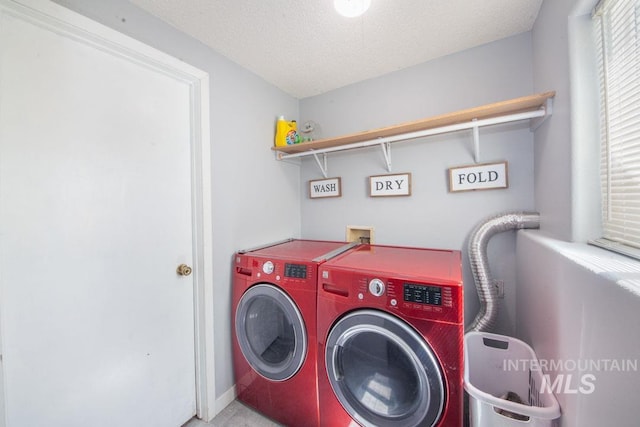 washroom with laundry area, a textured ceiling, and washer and dryer