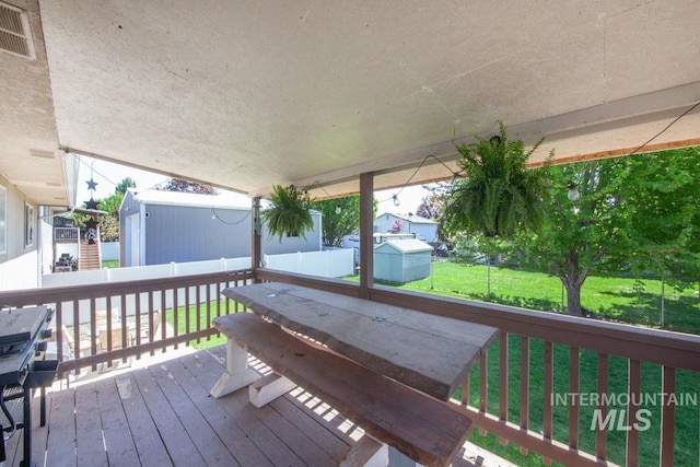 wooden deck featuring a lawn, a fenced backyard, and visible vents