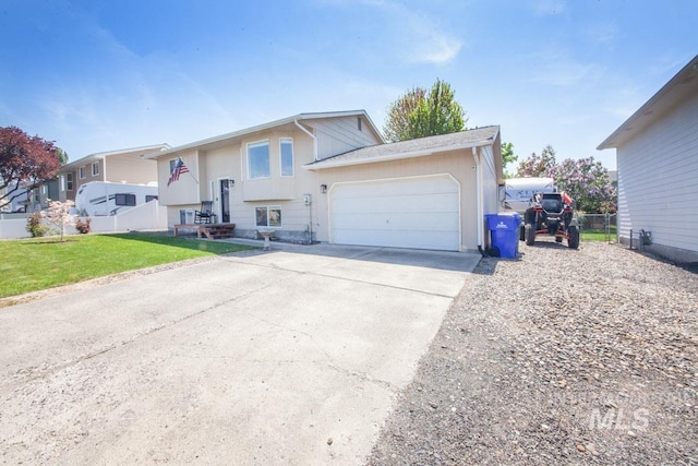bi-level home with fence, an attached garage, concrete driveway, and a front lawn