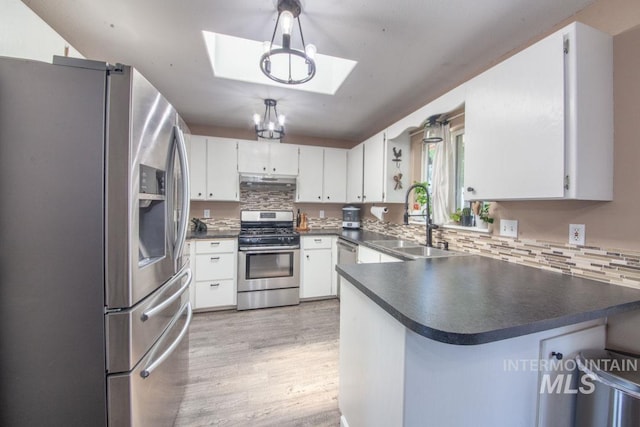 kitchen with a peninsula, a sink, light wood-style flooring, a skylight, and stainless steel appliances