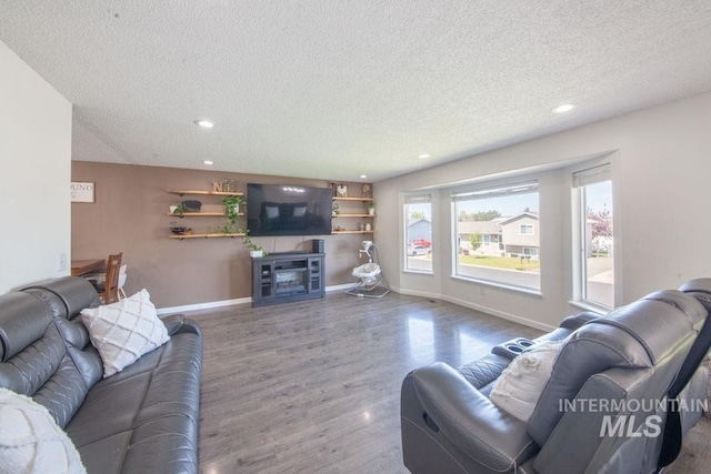 living area with recessed lighting, a textured ceiling, and wood finished floors