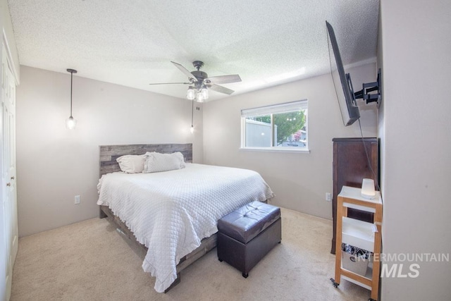 bedroom with a ceiling fan, a textured ceiling, and carpet