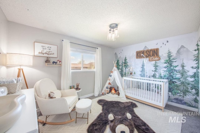 bedroom featuring a textured ceiling, a crib, and baseboards