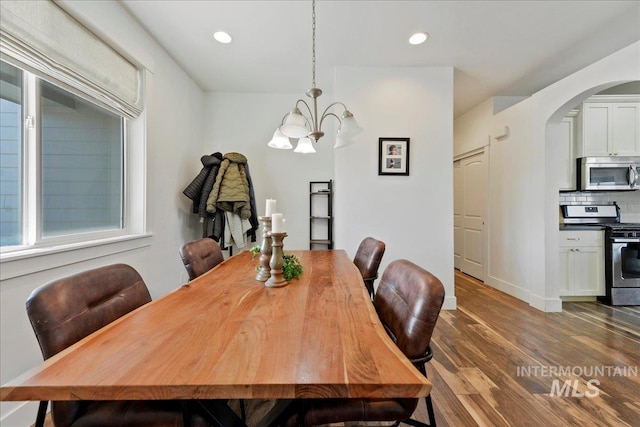 dining space with arched walkways, a notable chandelier, recessed lighting, dark wood-type flooring, and baseboards