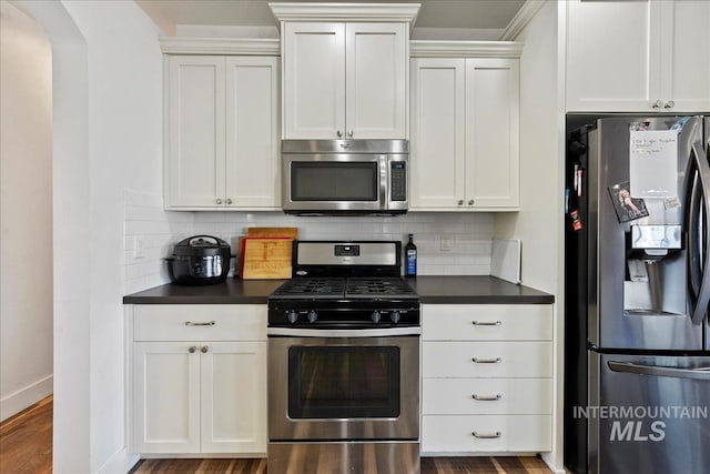 kitchen with dark countertops, appliances with stainless steel finishes, decorative backsplash, and white cabinets