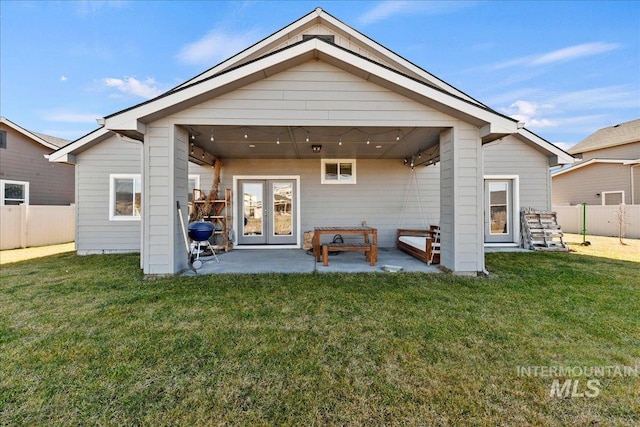 rear view of property featuring a patio, french doors, a lawn, and fence