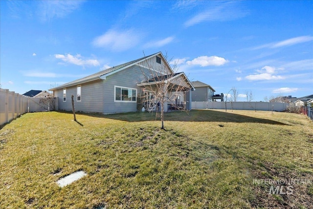 rear view of property featuring a fenced backyard and a lawn