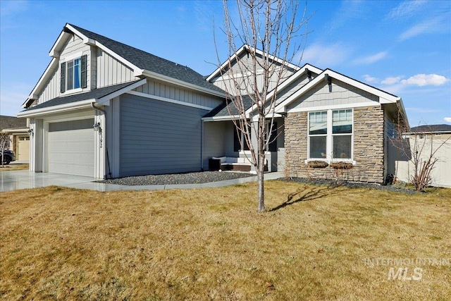 view of front of home with board and batten siding, a front yard, stone siding, and concrete driveway