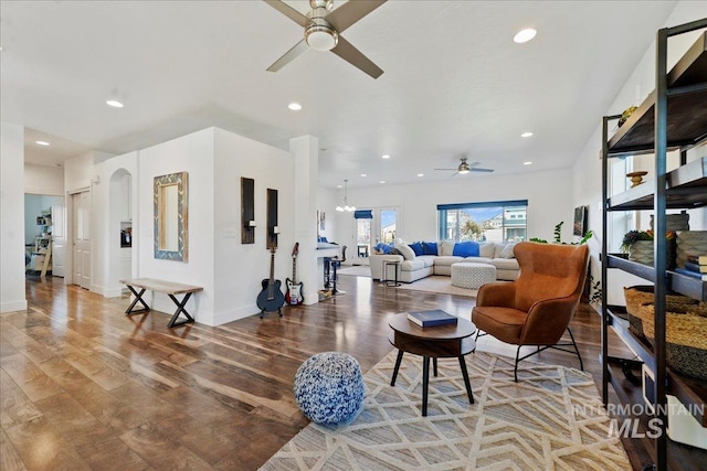 living room with baseboards, arched walkways, wood finished floors, and recessed lighting