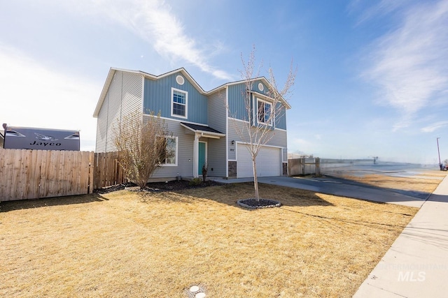 traditional-style home with board and batten siding, driveway, a garage, and fence