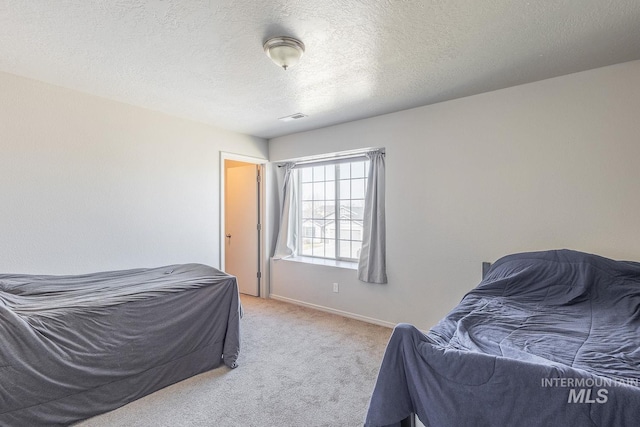 bedroom featuring visible vents, baseboards, light colored carpet, and a textured ceiling