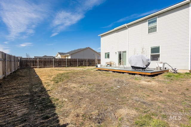 back of property with a deck, a yard, and a fenced backyard