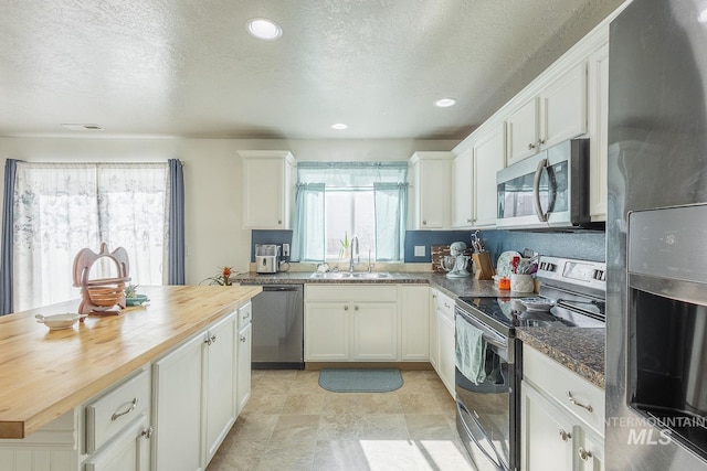 kitchen with plenty of natural light, butcher block counters, stainless steel appliances, and a sink