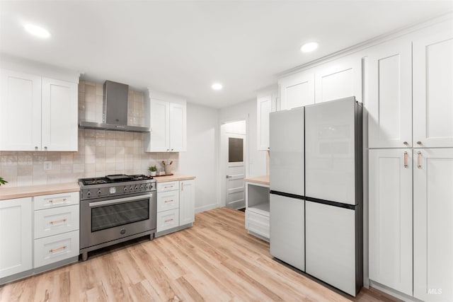 1600 E Victory Rd, Boise, ID 83706 - kitchen with stainless steel stove, wall chimney range hood, freestanding refrigerator, light countertops, and white cabinetry