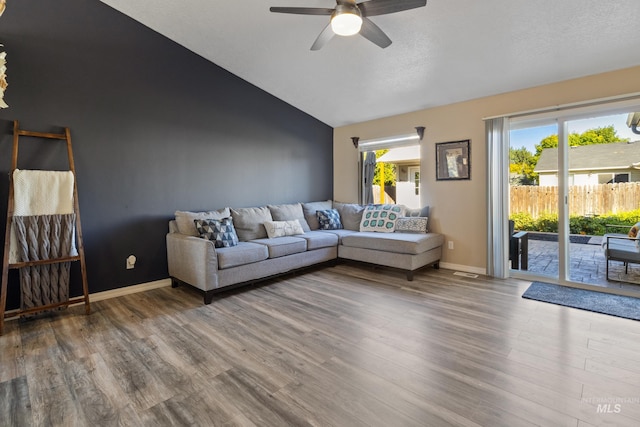 living room featuring wood-type flooring, vaulted ceiling, and a wealth of natural light