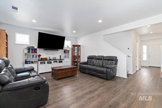 living room with stairway, dark wood-type flooring, visible vents, and recessed lighting