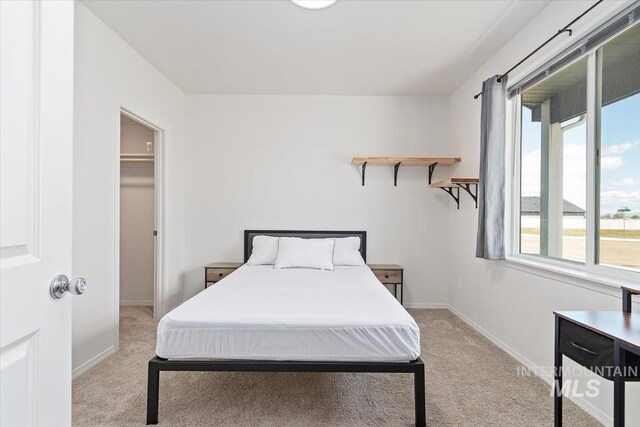 bedroom with baseboards, carpet flooring, and a walk in closet