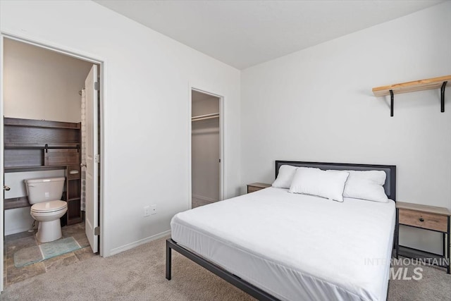 bedroom with a walk in closet, a closet, baseboards, carpet flooring, and ensuite bathroom
