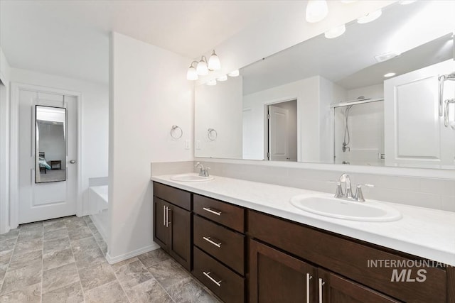 full bathroom featuring baseboards, a sink, double vanity, and a stall shower