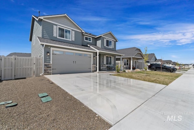 craftsman house with a gate, driveway, stone siding, fence, and a garage