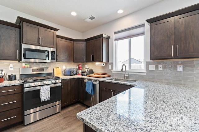 kitchen with dark brown cabinetry, stainless steel appliances, visible vents, and a sink