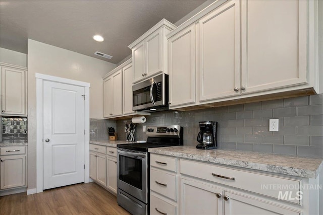 1123 Drexel Hill Ave, Caldwell, ID 83605 - kitchen featuring appliances with stainless steel finishes, light wood-style floors, tasteful backsplash, white cabinets, and recessed lighting