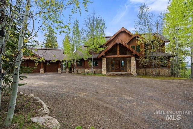 370 Blackhawk Lake Dr, Mccall, ID 83638 - view of front facade with stone siding, an attached garage, and dirt driveway