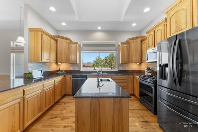 4019 E Man O War Dr, Nampa, ID 83686 - kitchen featuring appliances with stainless steel finishes, a kitchen island with sink, dark stone counters, light wood finished floors, and tasteful backsplash